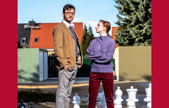 Vorschaubild zum Theaterstück mit einem Mann und einer Frau die an einem Outdoor-Schachfeld stehen.