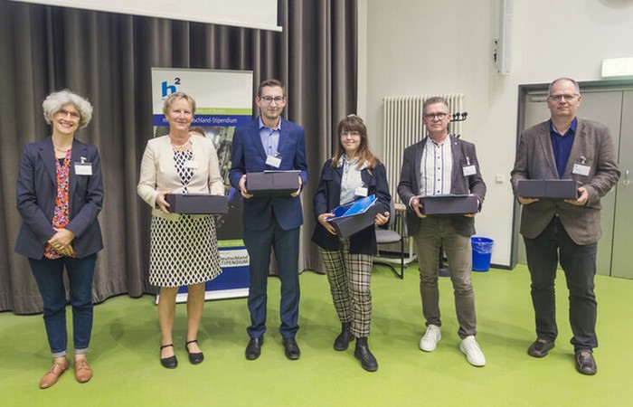 Vetreter der Hochschule mit Stapeln von Deutschlandstipendien.