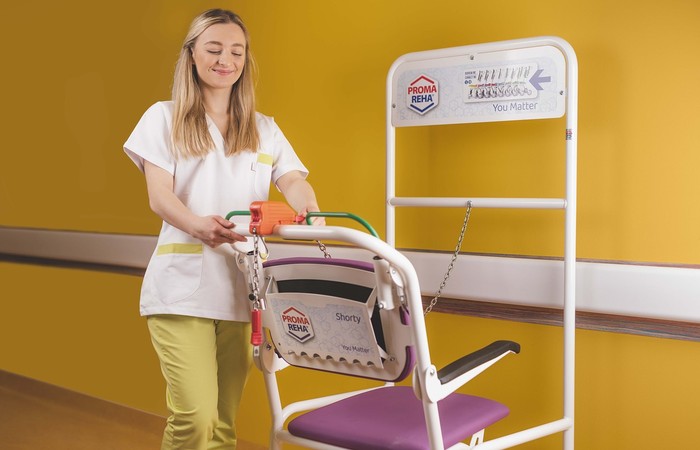 Mitarbeiterin bei der Verwendung eines Reha-Stuhls.