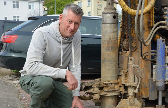 Foto des Absolventen Christian Recklies neben einer Baumaschine.