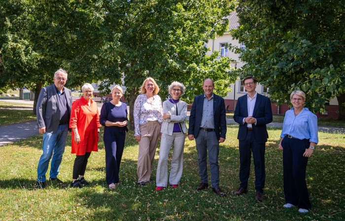 Mitglieder des Kuratoriums stehen gemeinsam im Grünen des Campus.