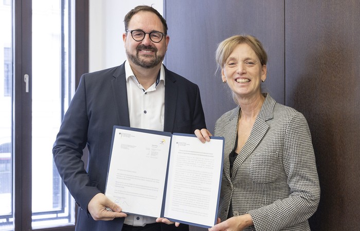 Foto von Bundesministerin Karin Prien und Prof. Dr. Ralf Lottmann beim Halten eines Dokuments.