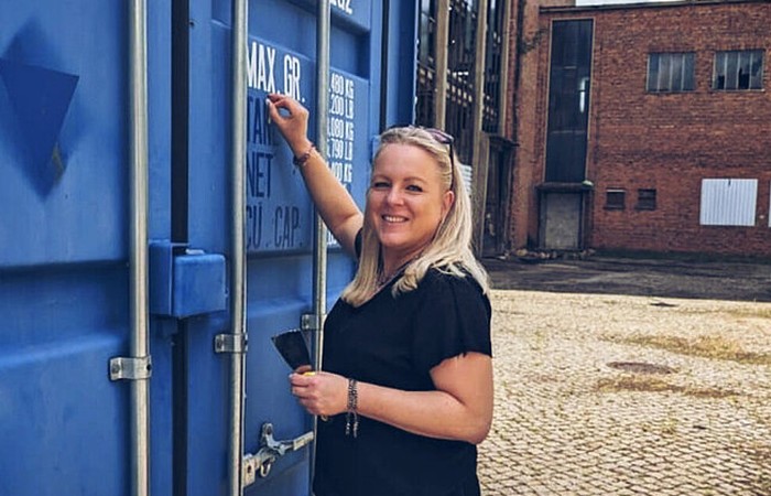 Foto der Absolventin Anja Müller, welche lächelnd einen Container in einem Innenhof beschriftet.