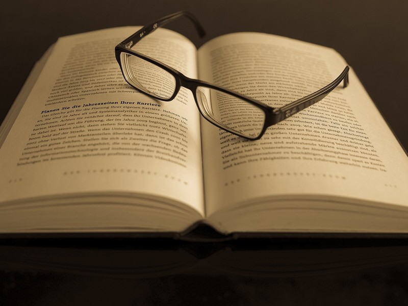 Eine Brille liegt auf einem offenen Buch.