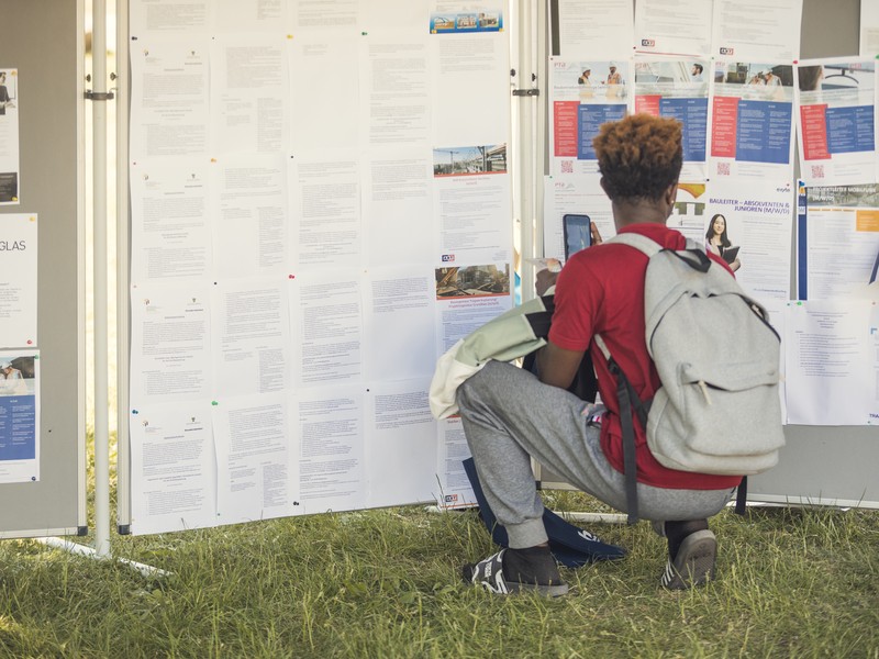 Besucher betrachtet Jobangebote auf einer Jobmesse auf dem Campus.