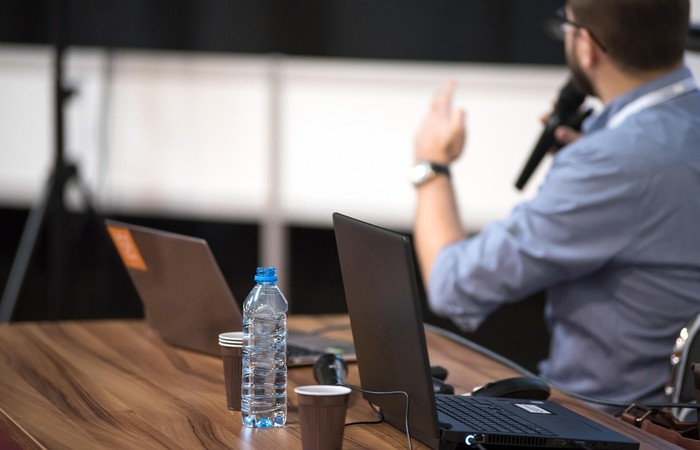 Foto einer präsentierenden Person mit Laptops am Tisch.