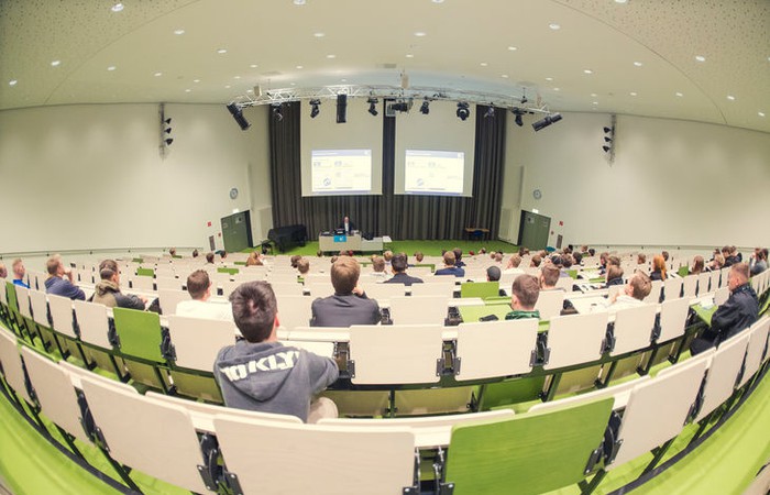 Studierende und Lehrender in einem Hörsaal.